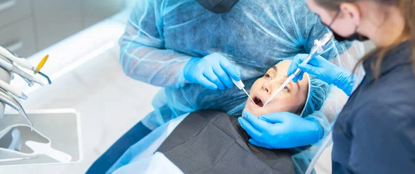 口腔治療を提供歯科椅子の女性患者と男性歯科医とアシスタント — ストック写真