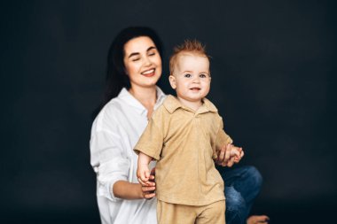 Bir kadın küçük bir çocuğu nazikçe kollarında tutuyor ve anne ile çocuk arasında sevgi ve şefkat bağı kuruyor..