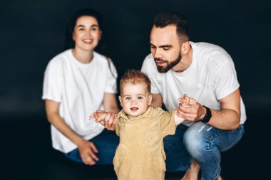 Bir adam, kadın ve çocuk bir arada durup gülümsüyor ve fotoğraf için poz veriyorlar..