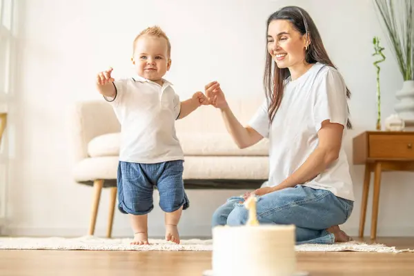 stock image A woman is seated on the floor beside a baby, engaging in a bonding moment.