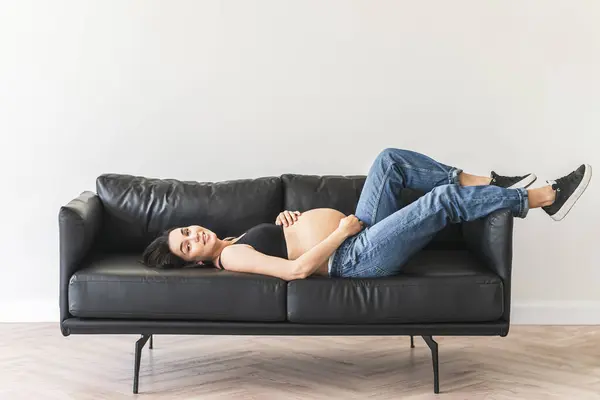 一个女人躺在房间里的一张黑色沙发上 免版税图库照片