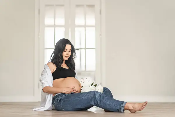 Hamile Bir Kadın Elinde Renkli Bir Buket Çiçekle Yerde Oturuyor Stok Fotoğraf