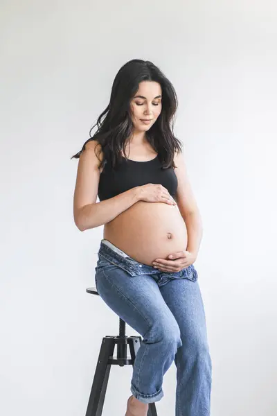 一个孕妇坐在这张照片中的凳子上 图库图片