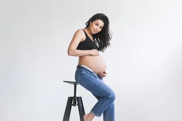 Μια Έγκυος Γυναίκα Στέκεται Ένα Σκαμνί Ένα Δωμάτιο Κρατώντας Έναν Royalty Free Εικόνες Αρχείου