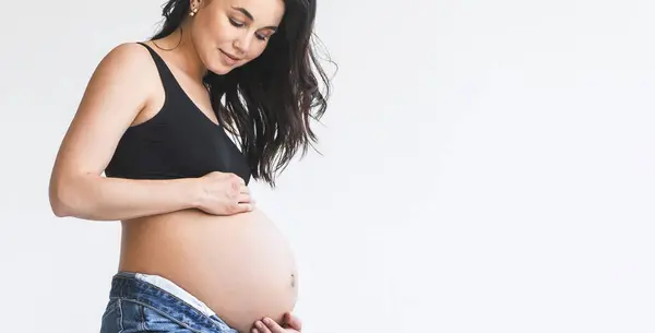 Een Zwangere Vrouw Met Een Zwart Topje Spijkerbroek Die Vol Stockfoto