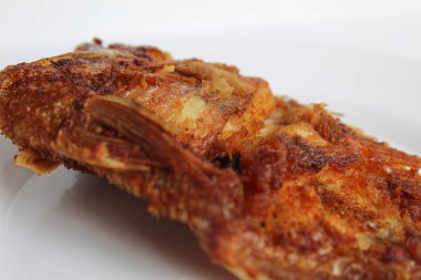 Beyaz bir tabakta kızarmış kırmızı tilapia balığı, beyaz arka planda izole edilmiş.