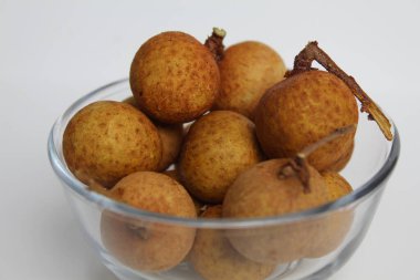 Beyaz arka planda izole edilmiş şeffaf bir kasede Longan meyvesi.