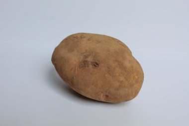 Kabuğu soyulmamış, toprak kaplı, beyaz arka planda izole edilmiş bir patates.