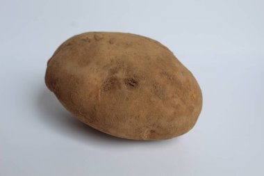 Kabuğu soyulmamış, toprak kaplı, beyaz arka planda izole edilmiş bir patates.