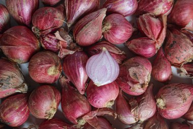 Beyaz zemin üzerinde soyulmamış kırmızı arpacık soğanı, düz uzanmış