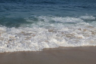 Boş kumsal. Açık deniz suyu, deniz dalgaları, deniz köpüğü ve beyaz kum.