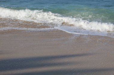 Boş kumsal. Açık deniz suyu, deniz dalgaları, deniz köpüğü ve beyaz kum.