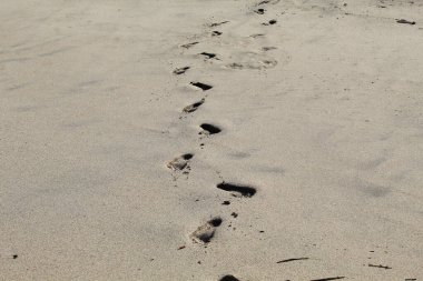 Kumsalda beyaz kum ve ayak izleri.