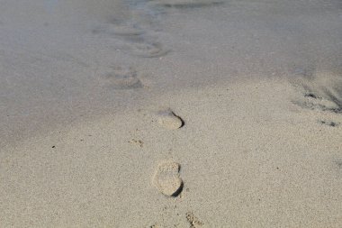 Kumsalda beyaz kum ve ayak izleri.
