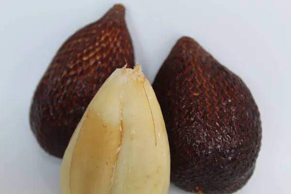 Soyulmuş ve soyulmamış yılan meyvesi ya da Salacca zalacca meyvesi, ya da salak, beyaz arka planda izole edilmiş.