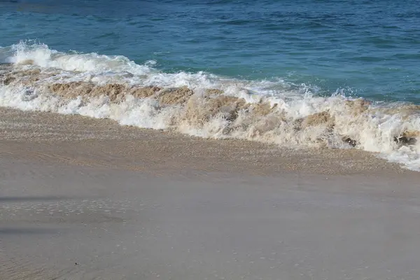 Boş kumsal. Açık deniz suyu, deniz dalgaları, deniz köpüğü ve beyaz kum.