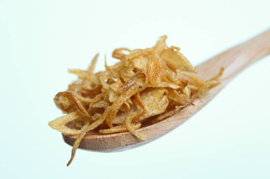 Fried onion crisp in a small wooden spoon. Isolated on white background. clipart