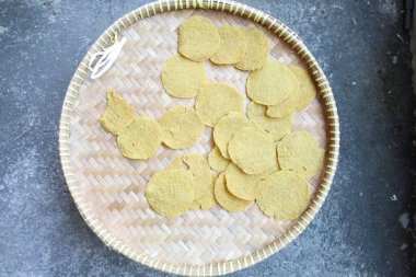 Kerupuk Nasi, Kerupuk Gendar or Rice Crackers, before fried. Food from Indonesia. Round shape. On a woven bamboo tray clipart