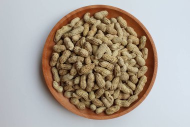 Groundnut, Goober or Monkey Nut, or Arachis hypogaea, on a wooden plate, isolated in white background. Ready to eat as snack clipart