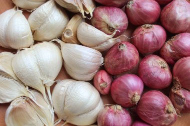 Garlic cloves and red onion or shallots on wooden plate, isolated on white background clipart