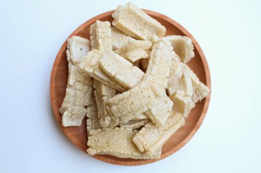 Kerupuk panjang, Indonesian snack or food condiment. Fried tapioca flour in long shape. On wooden plate, isolated on white background clipart