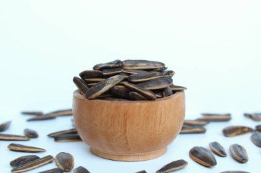 Pile of sunflower seed on a wooden bowl. Sunflower seed with striped shell. Isolated on white background clipart