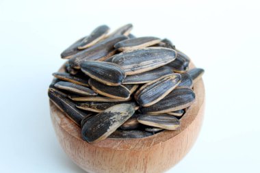 Pile of sunflower seed on a wooden bowl. Sunflower seed with striped shell. Isolated on white background clipart