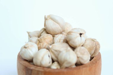 Dried cardamom fruit and seeds in wooden bowl, isolated on white background clipart