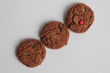 Beyaz arka planda izole edilmiş renkli şekerli üç parça çikolatalı kurabiye. Üst görünüm veya düz uzanma