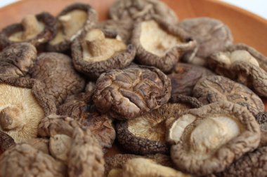 Dried paddy straw mushroom, or straw mushroom, or Volvariella volvacea, on wooden plate clipart