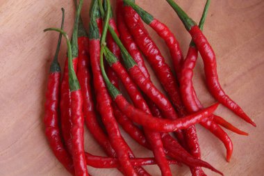 Fresh curly red chilies or cabe merah keriting, on a wooden plate. Main ingredient to make sambal in Indonesia. Flat lay or top view clipart