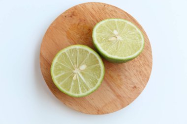 Halves of Green Lime, on wooden base, isolated on white background. Flat lay or top view clipart