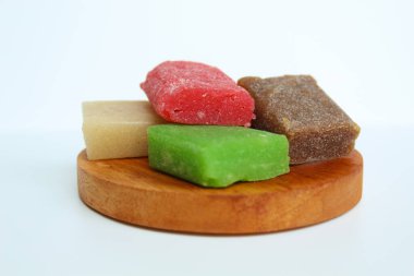 Yangko is traditional snack from Yogyakarta, Indonesia. Made from glutinous rice powder. Colorful yangko on wooden plate, isolated on white background clipart