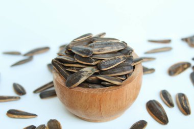 Pile of sunflower seed on a wooden bowl. Sunflower seed with striped shell. Isolated on white background clipart