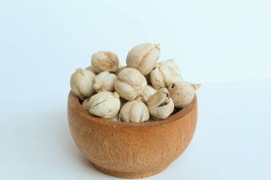 Kurutulmuş kakule meyvesi ve tohumlar ahşap kasede, beyaz arka planda izole.