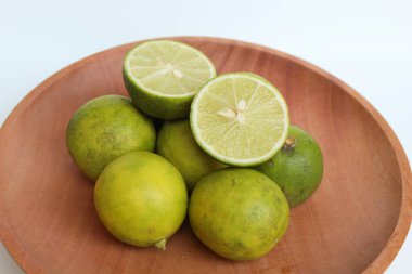 Halves of Green Limes, on wooden plate, isolated on white background clipart