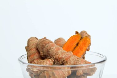 Turmeric or Curcuma longa rhizome in transparent bowl, isolated in white background. Side view clipart