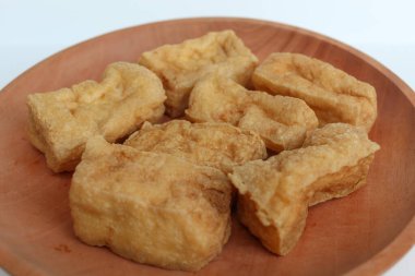 Ahşap tabakta kızarmış tofu, beyaz arka planda.