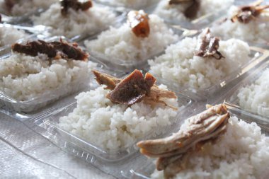 White rice and some slice of chicken, on plastic container, to be distributed clipart