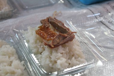 White rice and some slice of chicken, on plastic container, to be distributed clipart