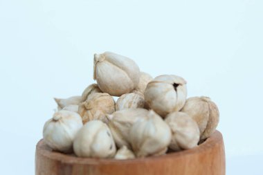 Kurutulmuş kakule meyvesi ve tohumlar ahşap kasede, beyaz arka planda izole.