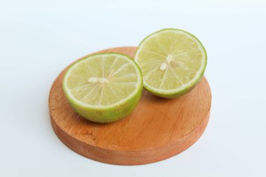 Halves of Green Lime, on wooden base, isolated on white background clipart