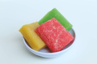 Yangko is traditional snack from Yogyakarta, Indonesia. Made from glutinous rice powder. Colorful yangko on plate plate, isolated on white background clipart