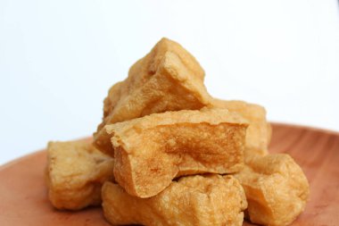 Ahşap tabakta kızarmış tofu, beyaz arka planda.
