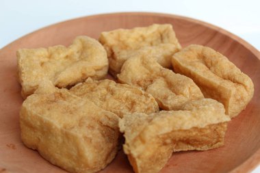 Ahşap tabakta kızarmış tofu, beyaz arka planda.