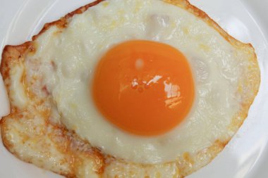 Sunny side up or fried chicken egg on white plate. Overcooked edge, crispy edge clipart