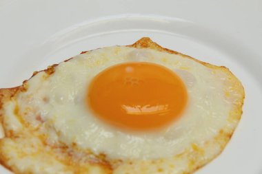 Güneşli tarafı ya da kızarmış tavuk yumurtası beyaz tabakta. Fazla pişmiş, çıtır çıtır.