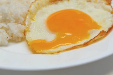 Güneşte pişmiş yumurta ve beyaz tabakta pilav. Çürük, sıvı ve kırık yumurta sarısı.