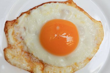 Güneşli tarafı ya da kızarmış tavuk yumurtası beyaz tabakta. Fazla pişmiş, çıtır çıtır.