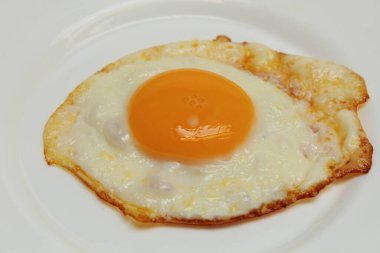 Güneşli tarafı ya da kızarmış tavuk yumurtası beyaz tabakta. Fazla pişmiş, çıtır çıtır.